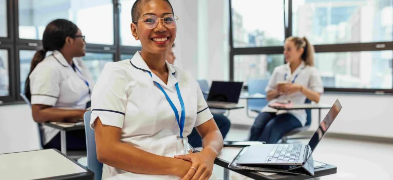 Smiling female nurse seated and studying for hesi exam