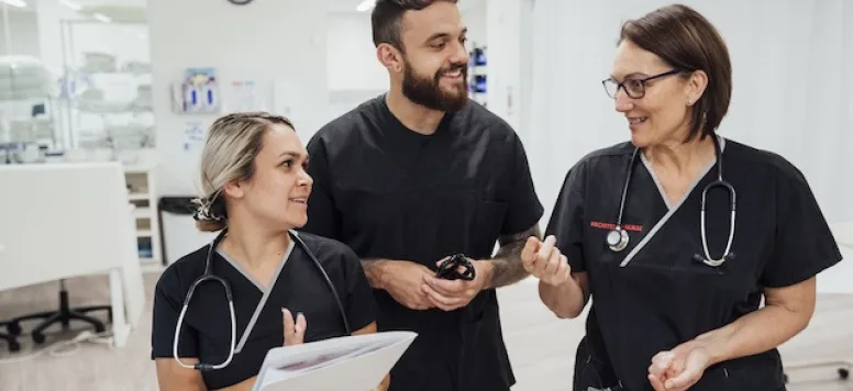 Two female nurses and one male nurse discussing teamwork in nursing