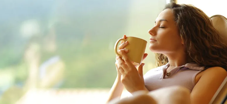 Woman hired by best travel nurse companies relaxes, drinks coffee before shift