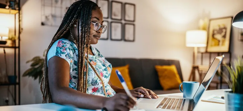 Woman wearing glasses looking at online psychiatric nurse practitioner programs on a computer