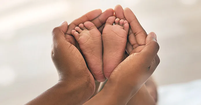 A mother holding her newborn babies feet in her hands