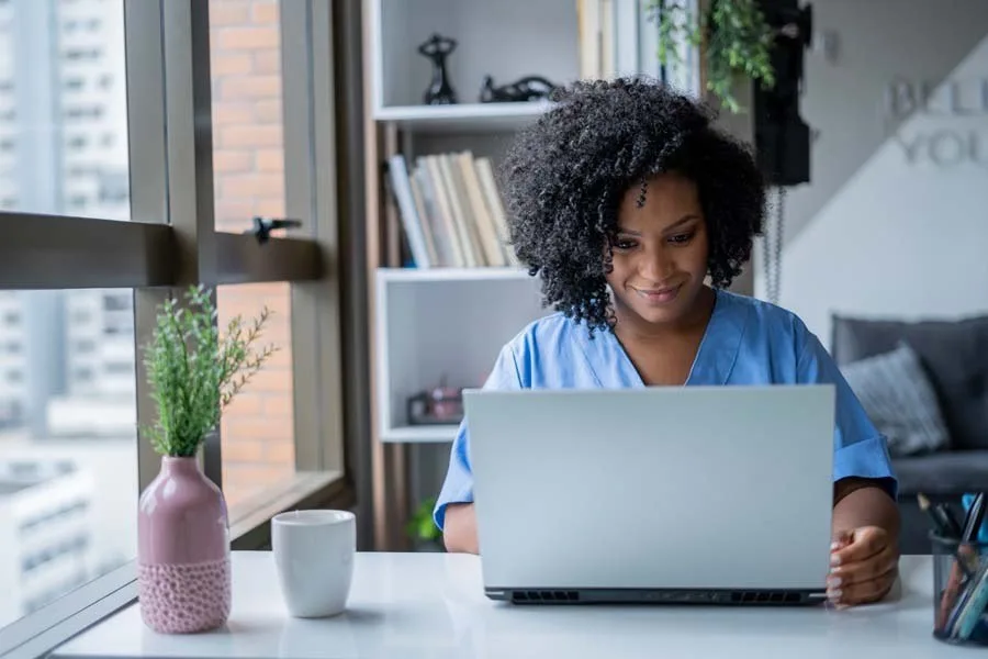 Nurse reviewing documents on laptop