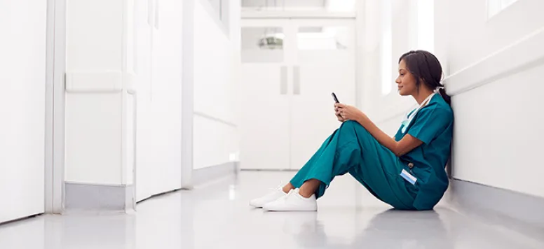 Nurse sitting in hallway looking at her phone