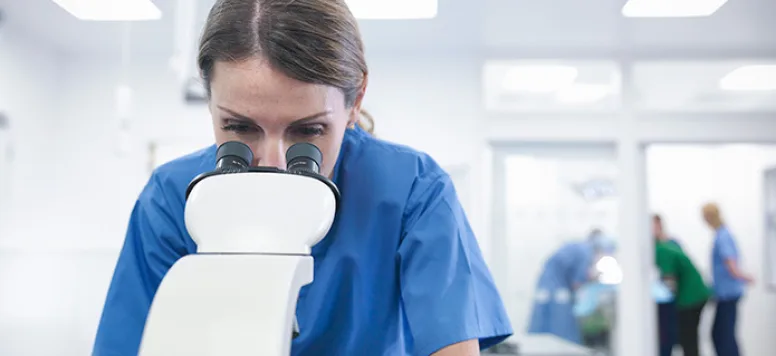 Nurse using microscope to review a sample