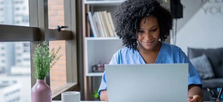 Nurse reviewing documents on laptop