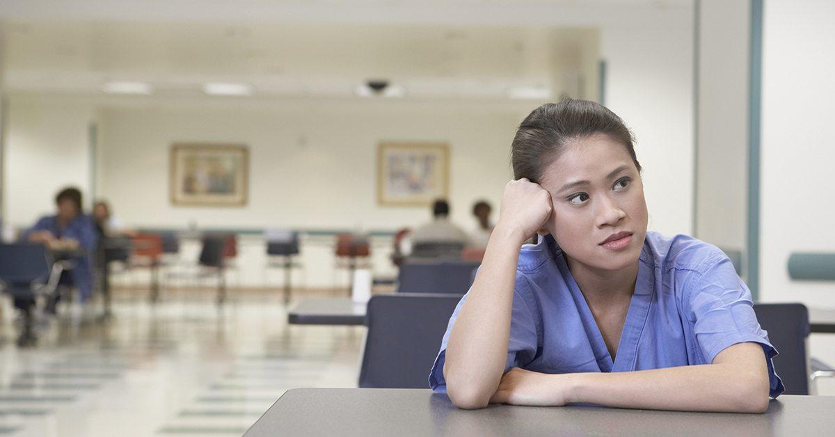 Nurse sitting at table leaning head on hand
