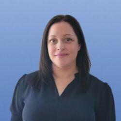 Nurse smiling in front of blue background who conducts nursing interviews.