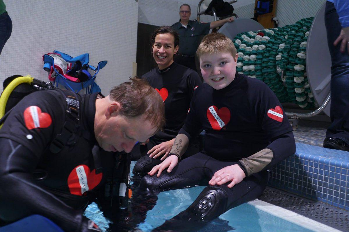 Diveheart staff prep a young participant for a scuba therapy session.