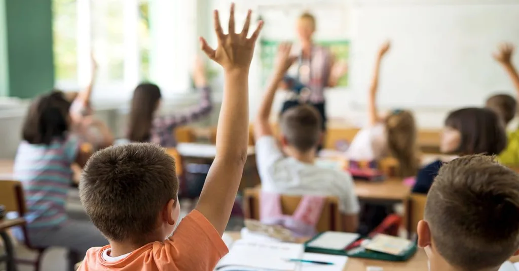 Children raising their hands in class