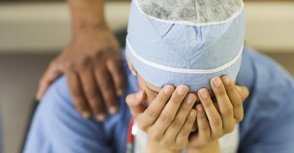 Nurse-with-scrub-cap-being-consoled-FB-GettyImages-103919098.jpg