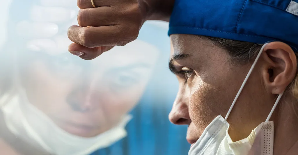 Nurse-with-mask-looking-out-window-FB-GettyImages-1219594528.jpg