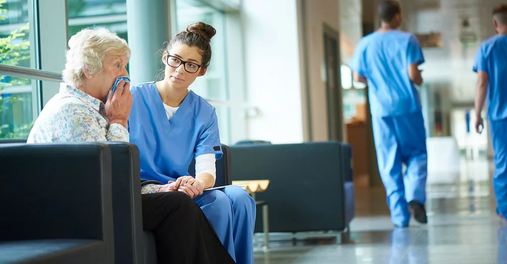 Nurse consoling elderly female patient