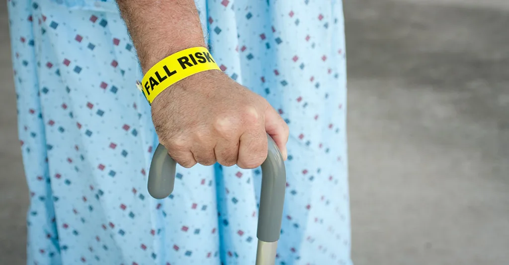 Fall risk hospital band on patient holding a cane