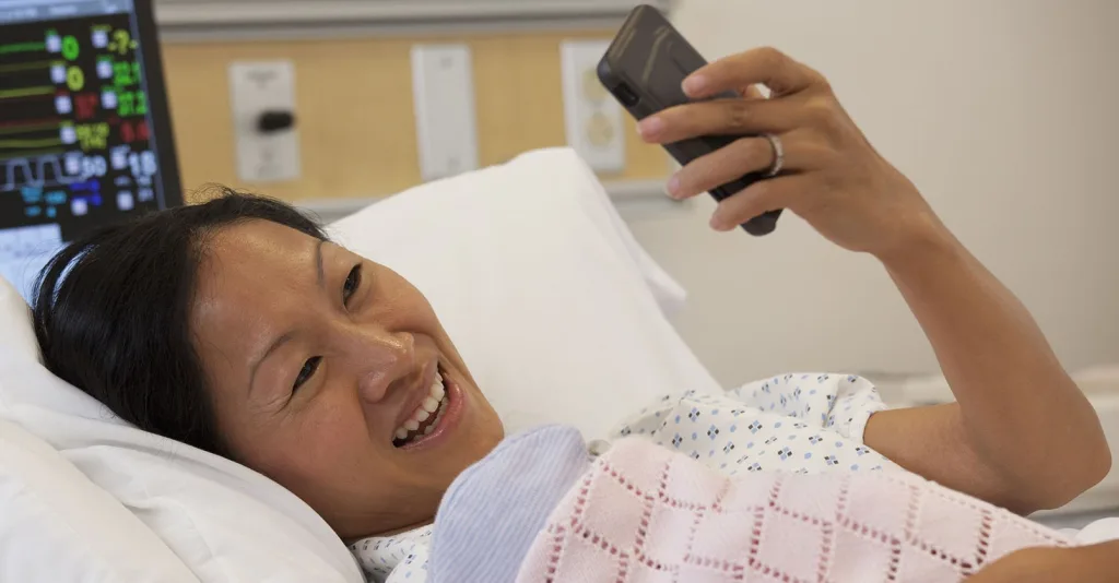 Patient in hospital bed on cell phone