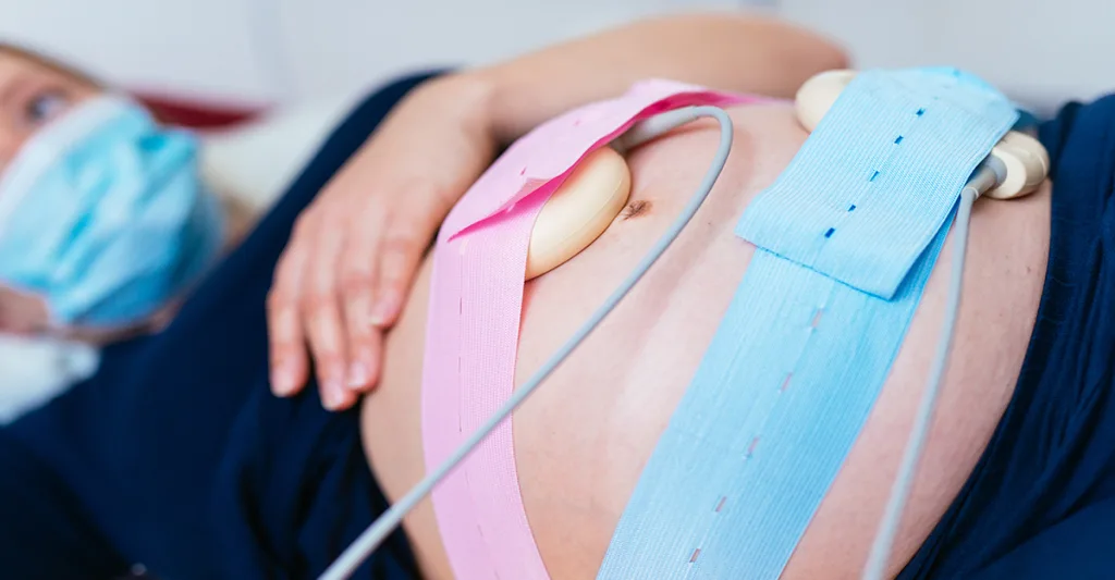 Electronic fetal monitoring on a woman's pregnant belly