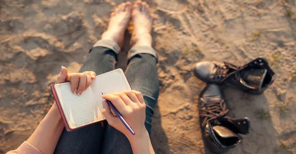 Woman-writing-in-journal-on-beach-FB-GettyImages-590301724.jpg