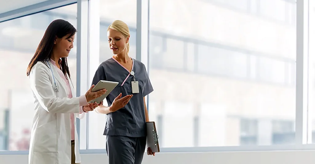 Female nurse talking to doctor in hallway