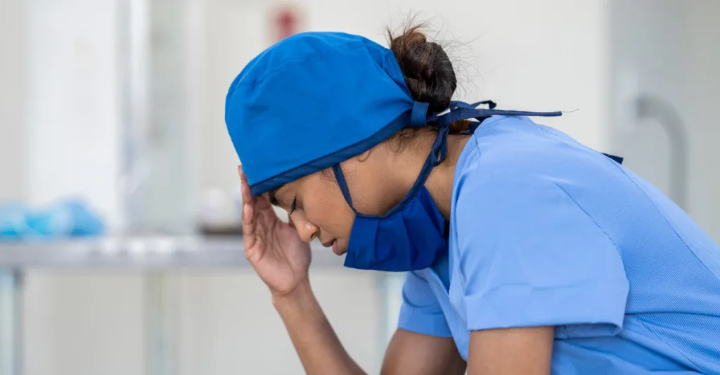 Stressed nurse with her head in her hands