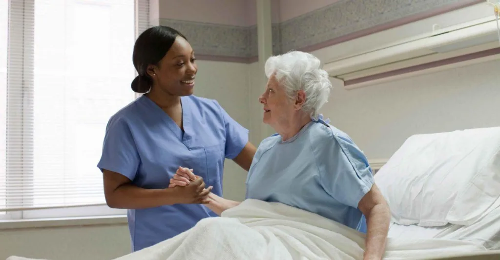 Nurse helping elderly patient in hospital bed