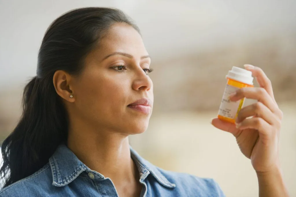 Woman looking at prescription bottle