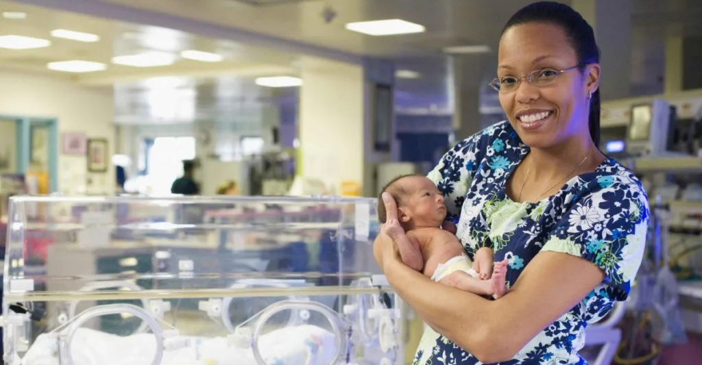 Neonatal nurse holding infant