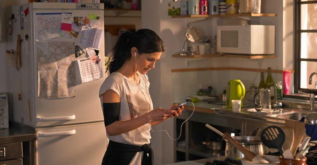 Women in kitchen listing to headphones