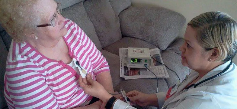 Nurse taking vitals on patient in her home