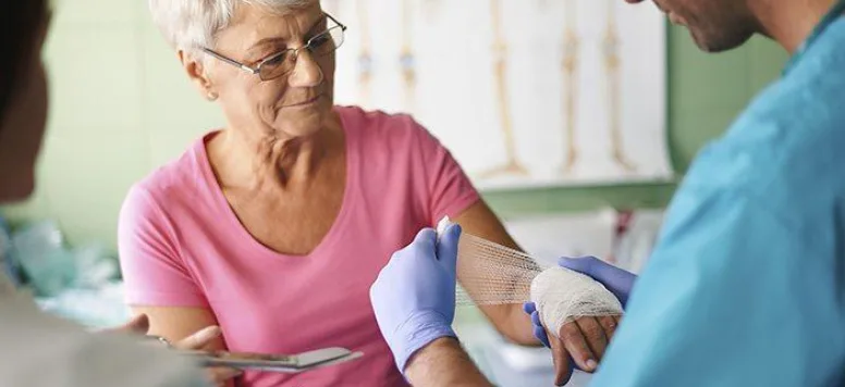 Nurse wrapping woman's hand due to a wound