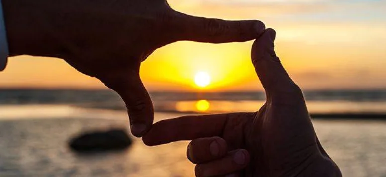 Hands pretending to take a picture of the sun