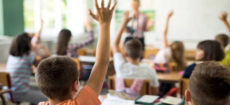 Children raising their hands in class