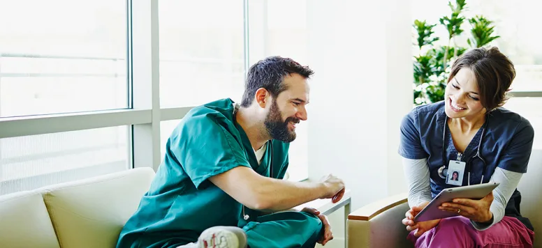 Two nurses reviewing tablet in the breakroom