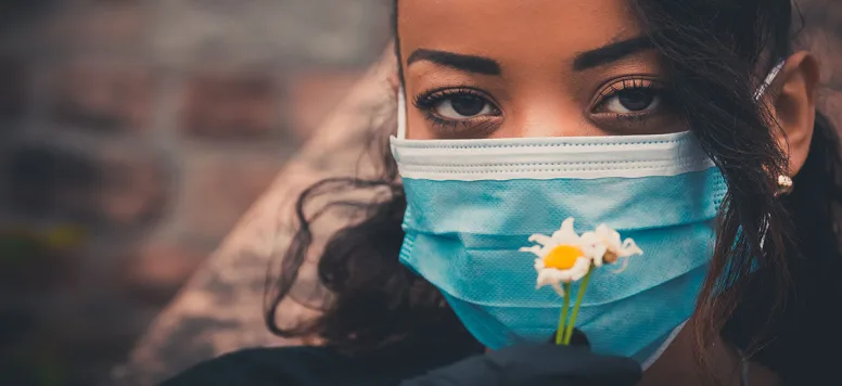 Nurse-with-mask-holding-daisy-FB-GettyImages-1223955109.jpg