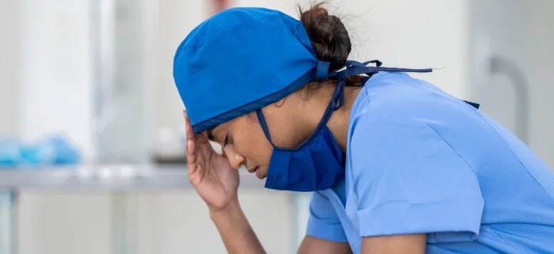 Stressed nurse with her head in her hands