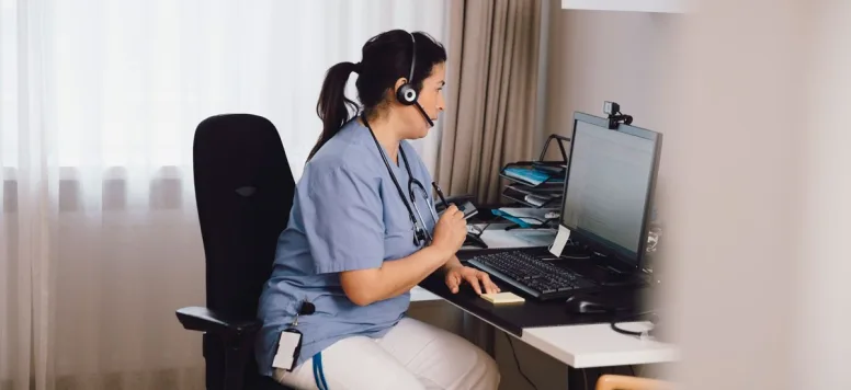 Nurse working on a computer with a headset