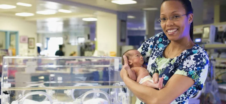 Neonatal nurse holding infant