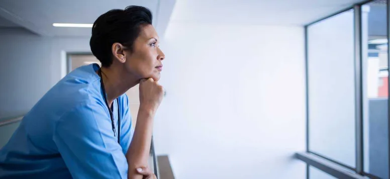 Female nurse looking out window