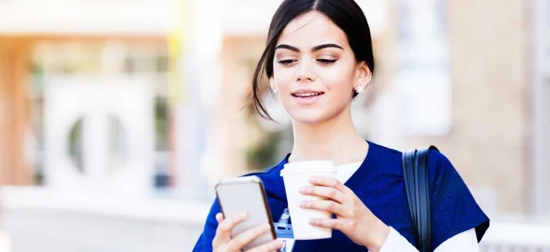 Nurse looking at her phone while drinking coffee