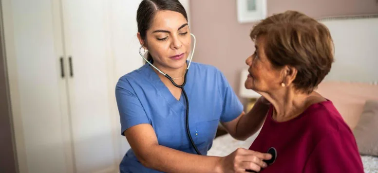 Nurse using her stethoscope to check female patients heart beat