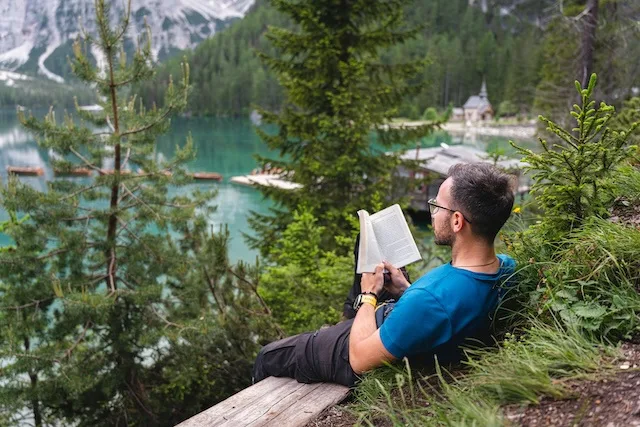 Man sitting in the woods reading a book