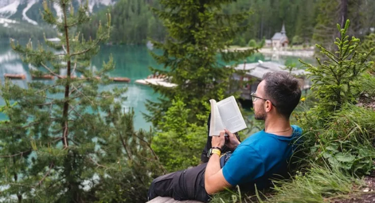 Man sitting in the woods reading a book