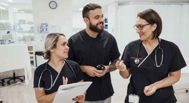 Two female nurses and one male nurse discussing teamwork in nursing