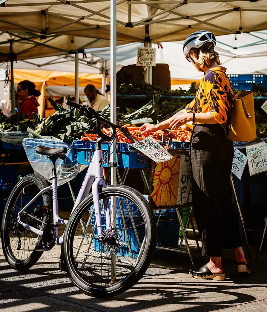 San Jose vegetable market near the new homes at SoFA One in Silicon Valley. Female biker in yellow shirt grabbing carrots.