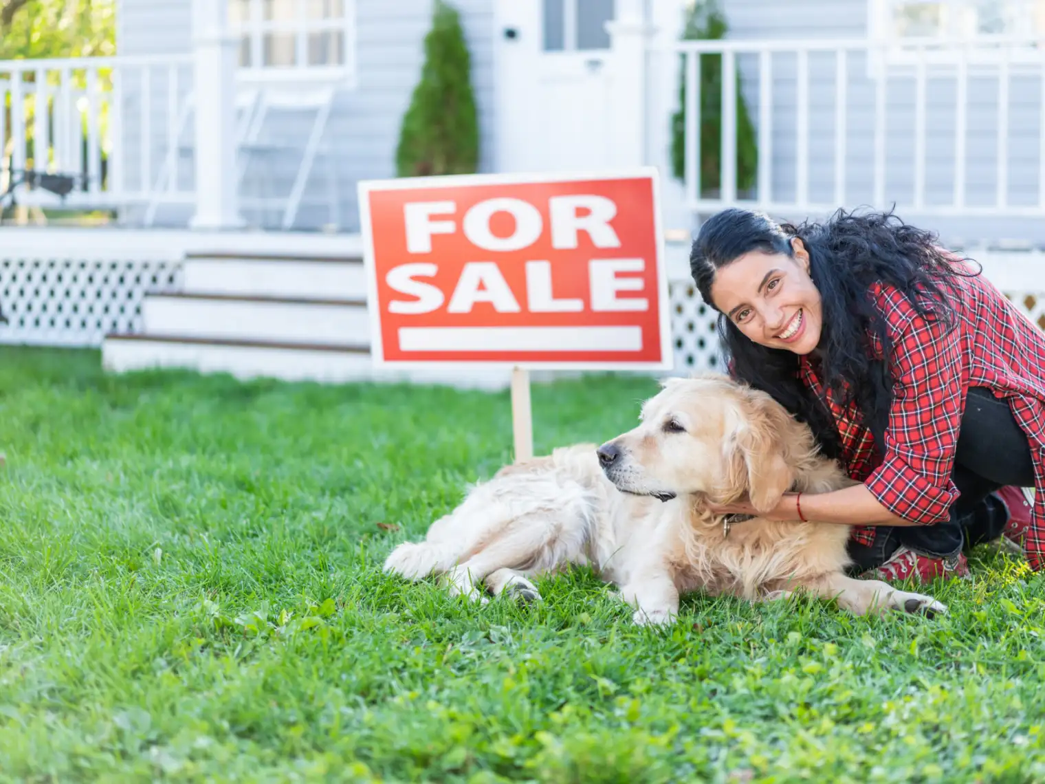 A woman pets her dog in front of home she has listed for sale.