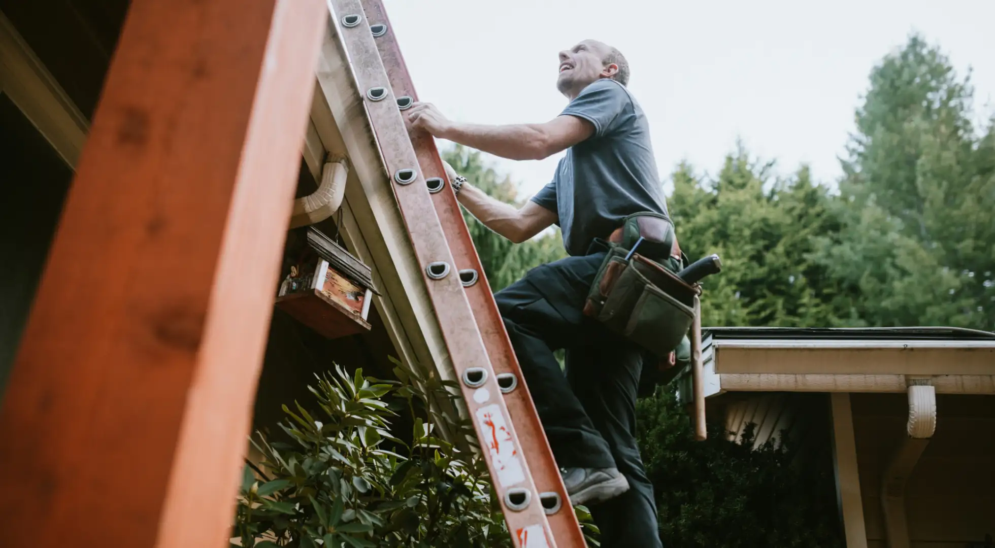A man climbs a ladder to his home's roof