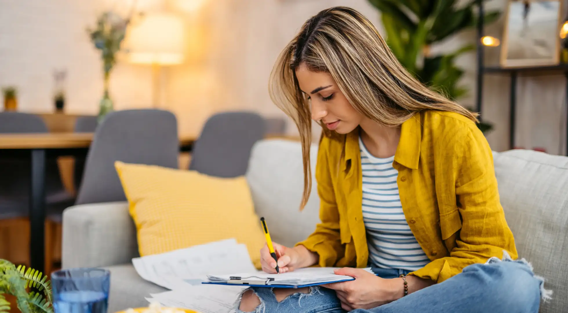 A woman reviewing documents on a couch, likely managing her HELOC in a cozy living room.