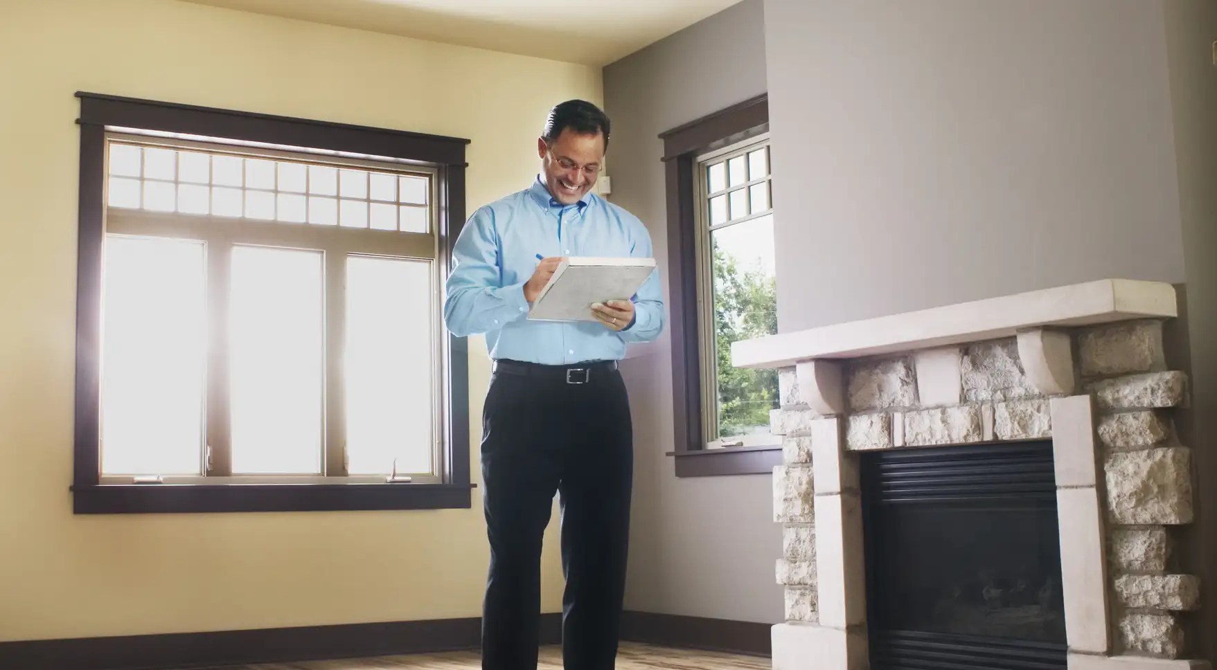 A man conducts a home appraisal, taking notes on a clipboard in an empty room.