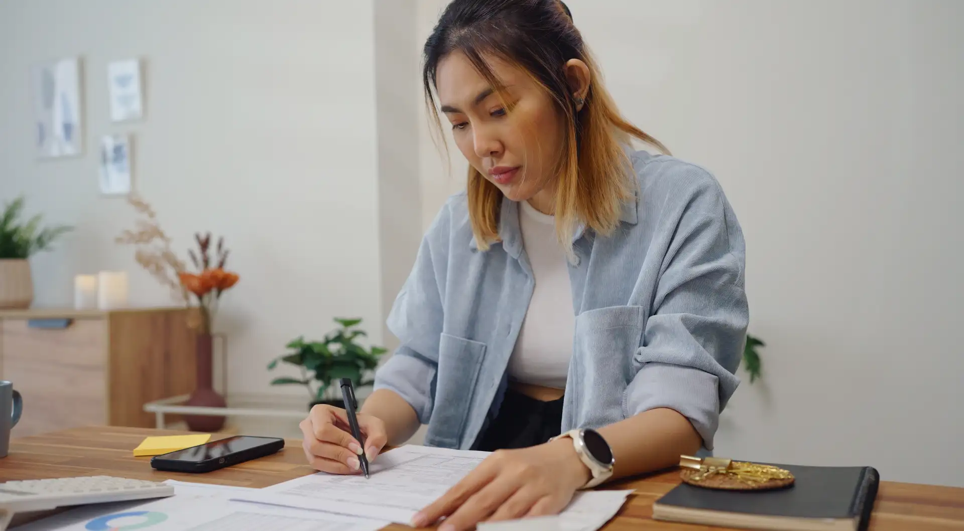 A woman reviews mortgage and PMI documents at her home office desk.