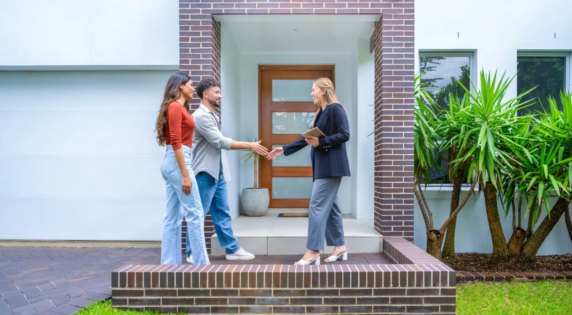 Real estate agent and couple in front of a house.