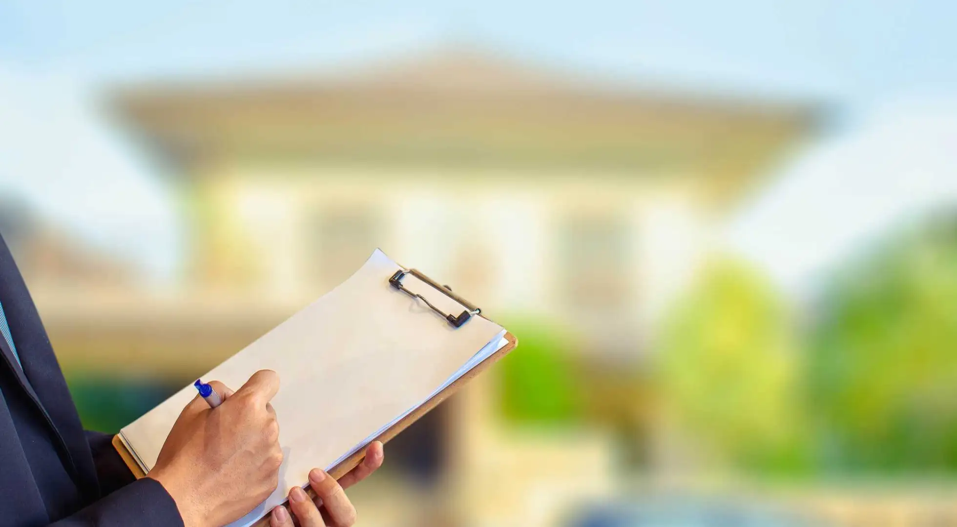 Closeup of home inspector's clipboard with a home in the background.