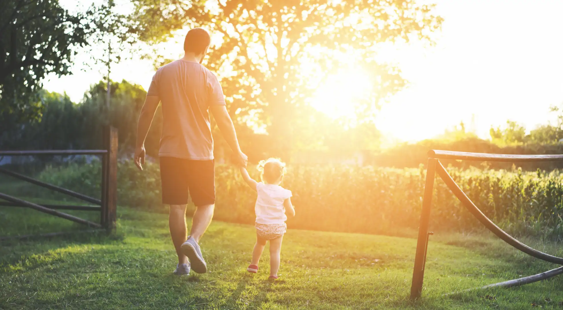 Man and daughter walk around field during sunset